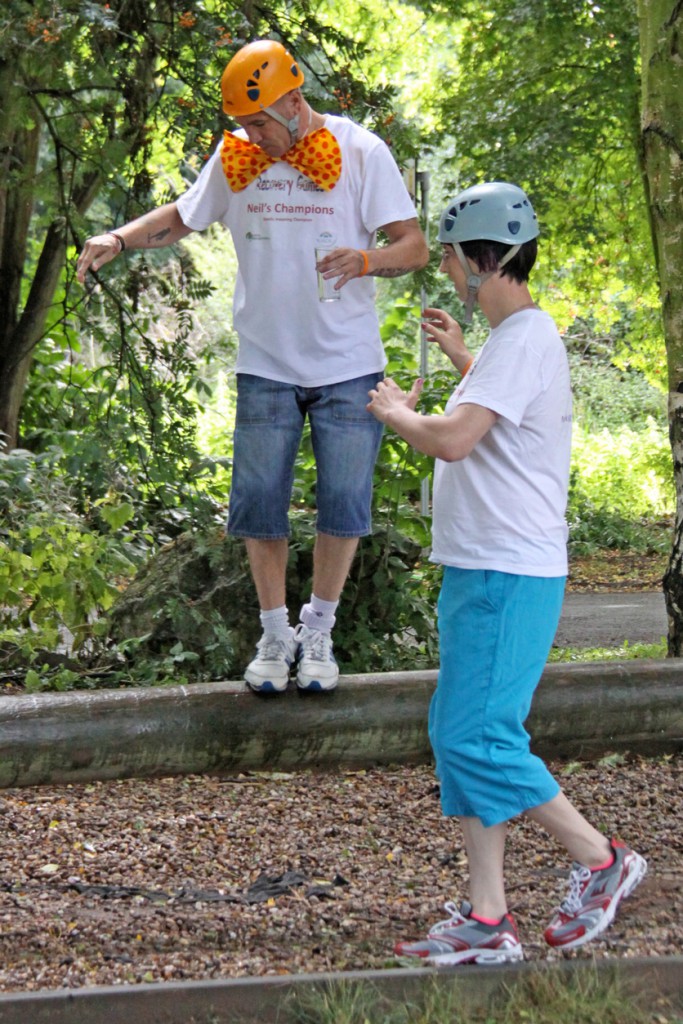 Two people helping each other walking on a log