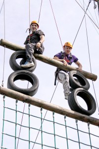 Two people climbing on an assault course