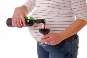 pregnant woman holding wine and wine glass