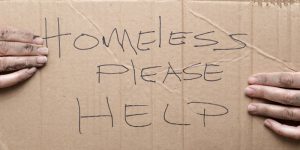person holding card saying homeless please help
